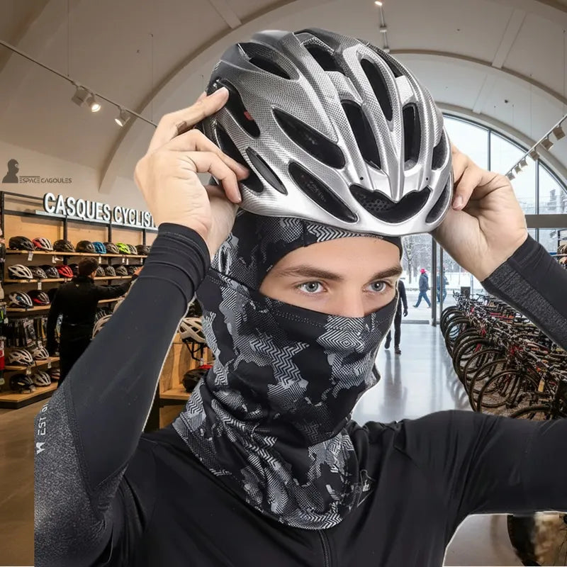 Cagoule pour faire du vélo portée par un cycliste en boutique spécialisée, matière polyester extensible, forme intégrale couvrant tête et cou, vue portée lors de la mise en place d’un casque de vélo - Espace Cagoules
