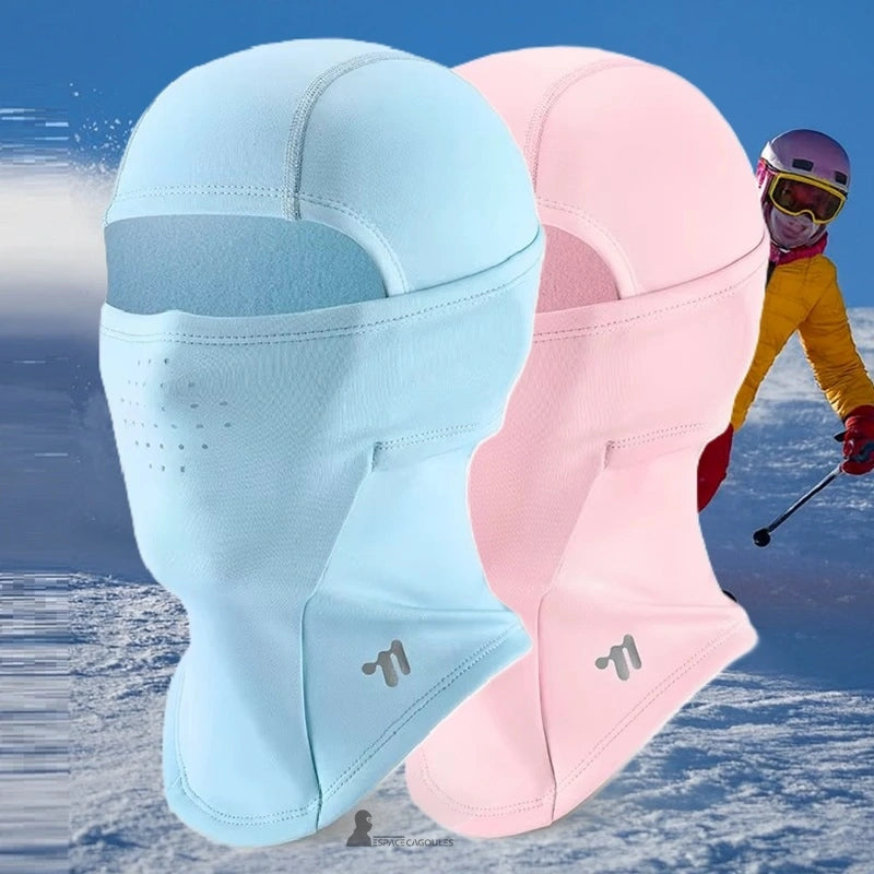 BlĂ„ och rosa fleece barnskidbalaclava presenterad mot en snöig bergsbakgrund med en skidĂ„kare i bakgrunden â Espace Cagoules
