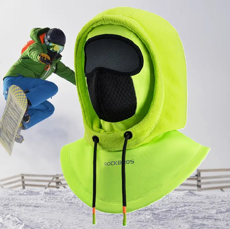 Snowboarder in the background wearing a neon green multifunctional ski hood with an ergonomic design, incorporating an adjustable fleece hood, a breathable fabric mouth area and a windproof bib covering the shoulders. Perfect for winter sports in a snowy environment.