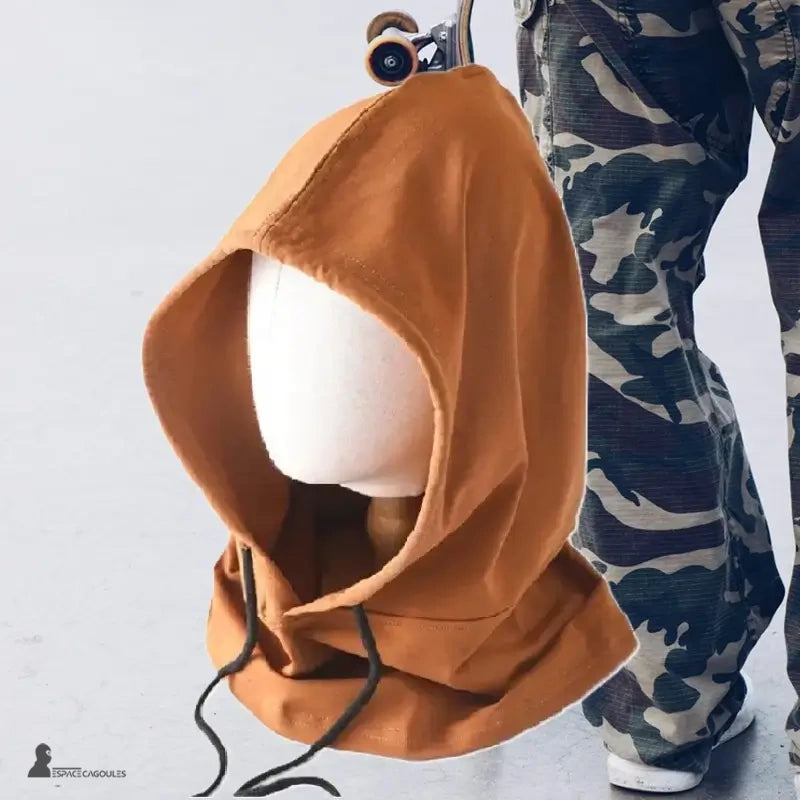 Cagoule streetwear marron clair en coton, présentée sur mannequin avec pantalon camouflage et skate, accessoire urbain idéal pour skateurs et amateurs de mode urbaine