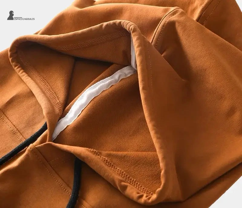 Cagoule streetwear marron en coton, gros plan sur les coutures et la texture du tissu, mettant en valeur la qualité et la finition soignée