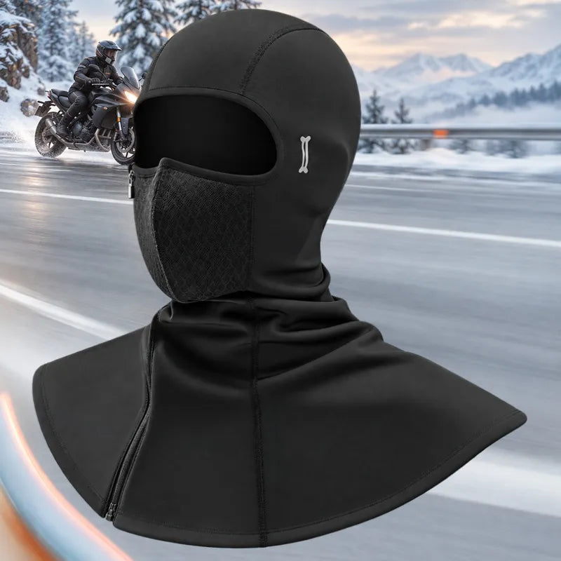 Cagoule thermique moto à plastron présentée devant une route enneigée, motard qui roule en arrière-plan - Espace Cagoules