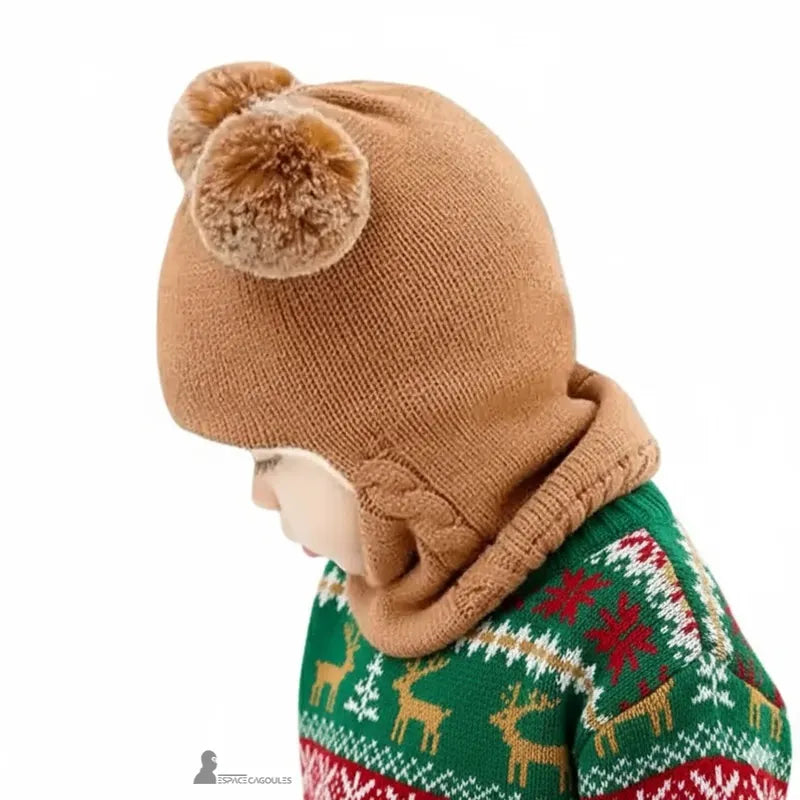 Cagoule tricot enfant marron vue de profil avec deux pompons, petit garçon portant un pull vert à motifs de rennes