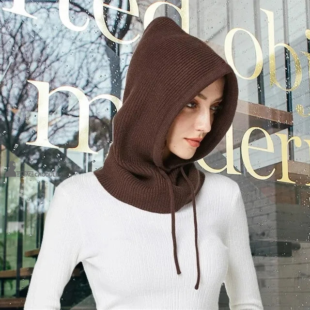Coffee brown women's knitted balaclava worn outdoors in front of a shop window in rainy weather