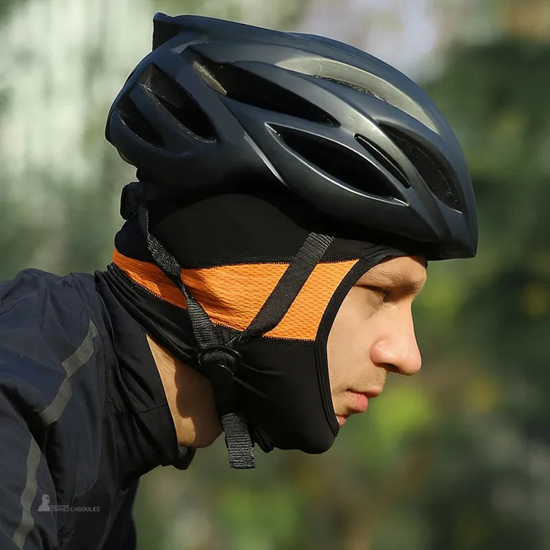 Black and orange silk bicycle balaclava worn under helmet, cyclist in action profile view