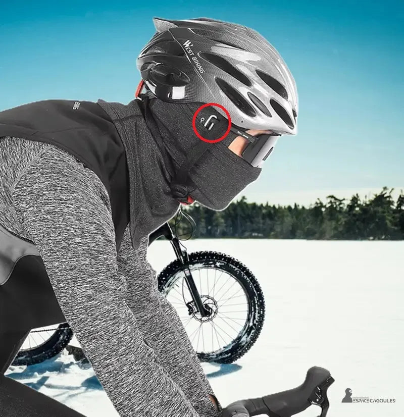 Cagoule vélo grand froid portée par cycliste en tenue hivernale avec casque et fond enneigé