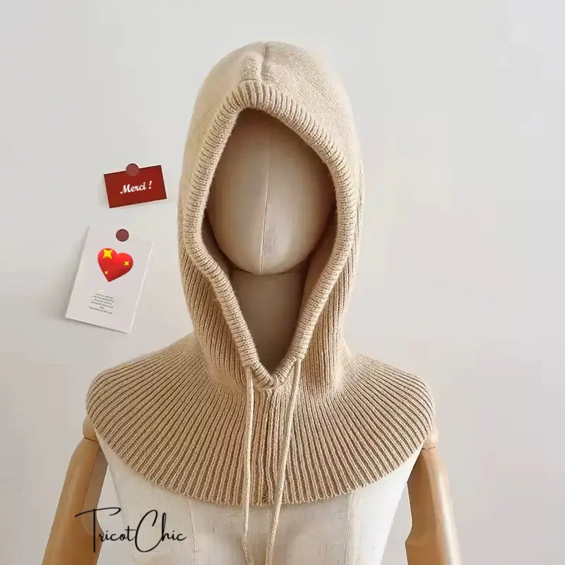 Capuche Tricot Femme en maille beige portée par un mannequin sur fond neutre. Conception élégante avec un tricot finement travaillé, couvrant la tête et le cou pour une protection contre le froid.