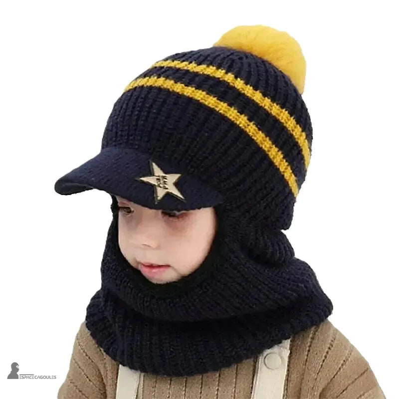 Casquette bonnet enfant bleu marine tricot avec rayures jaunes et pompon assorti, garçon portant un tablier beige