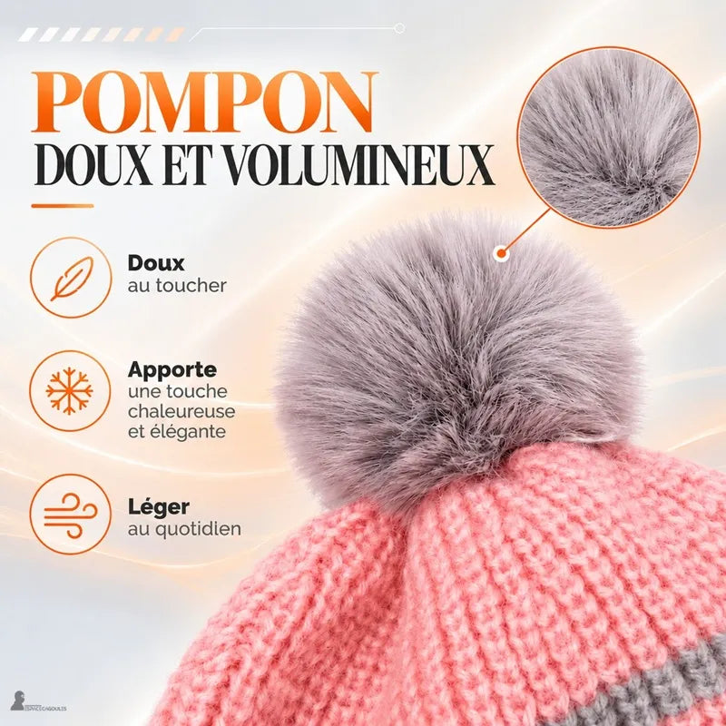 Casquette bonnet enfant rose tricot avec gros pompon gris, gros plan sur le détail du bonnet posé sur une table