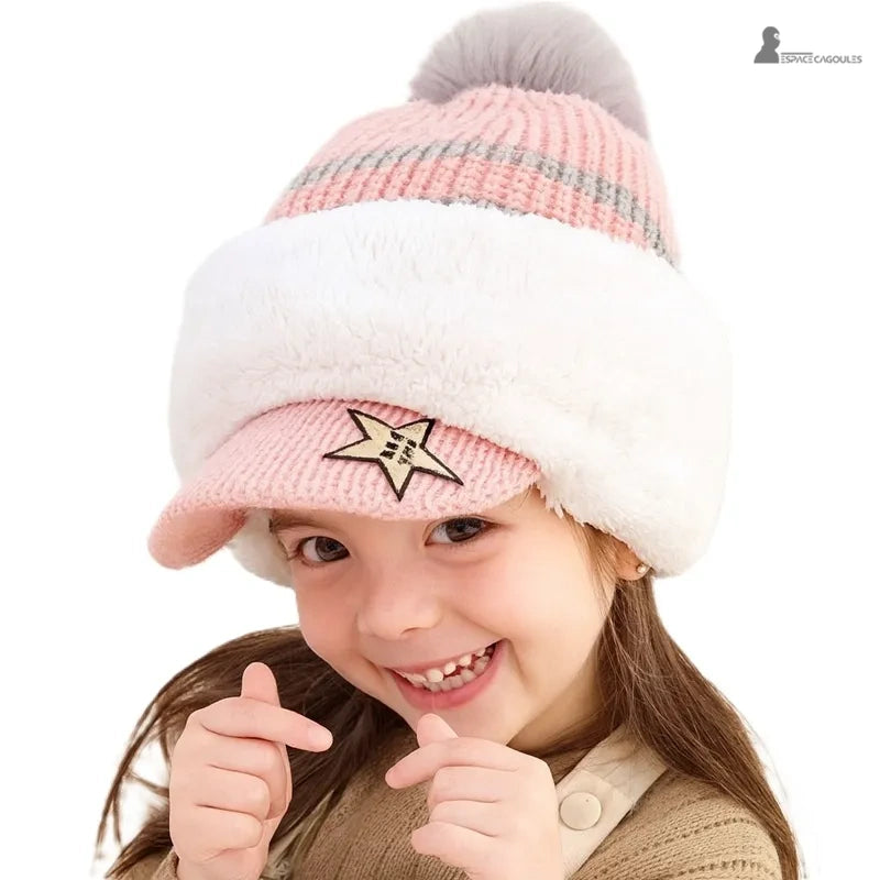 Casquette bonnet enfant rose avec pompon gris et large bande blanche, petite fille souriante en intérieur