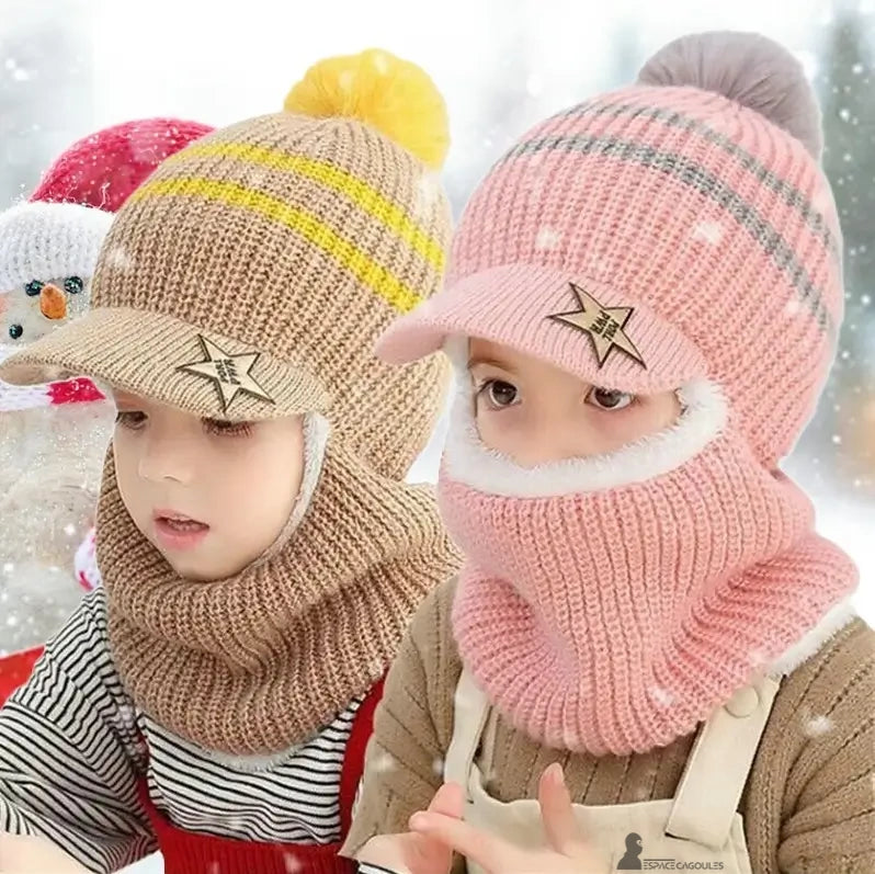 Casquette bonnet enfant tricot marron et rose avec pompon, deux enfants jouent dehors dans la neige devant un bonhomme de neige