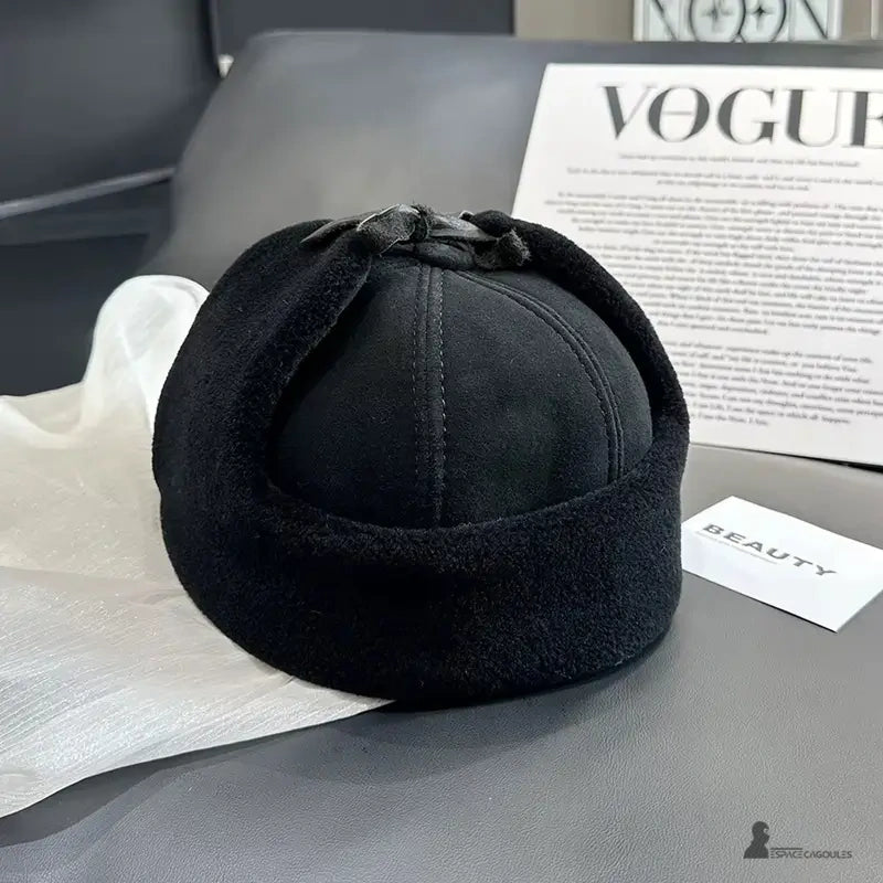 Svart chapka-keps med bakifrån med ullslag, placerad på en modern fåtölj