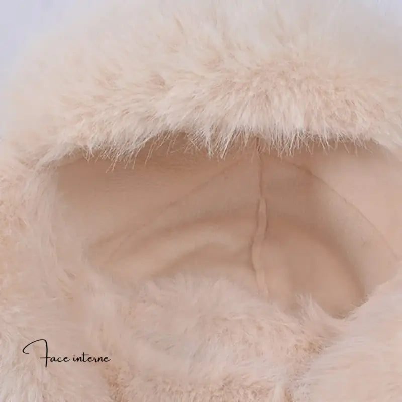 Nahaufnahme der Innenseite eines beigen russischen Damenhuts mit Leopardenmuster, der das weiche und warme Futter aus gestepptem Stoff hervorhebt, das von flauschigem Kunstfell umgeben ist.