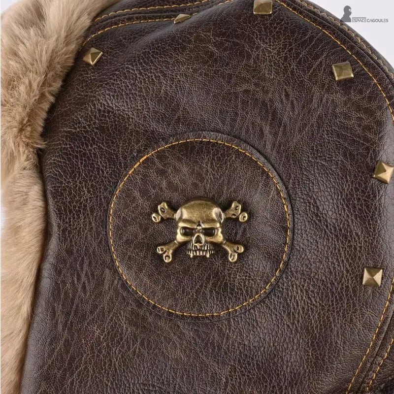 Chapka aviateur en cuir marron avec doublure en fausse fourrure, gros plan sur l’insigne métallique décoratif - Espace Cagoules
