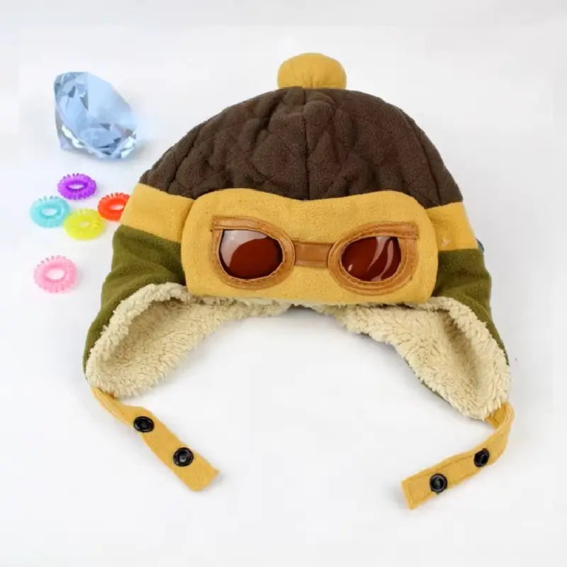 Brown and beige aviator children's hat in soft fleece, with aviator glasses and colorful décor, set on a white background.