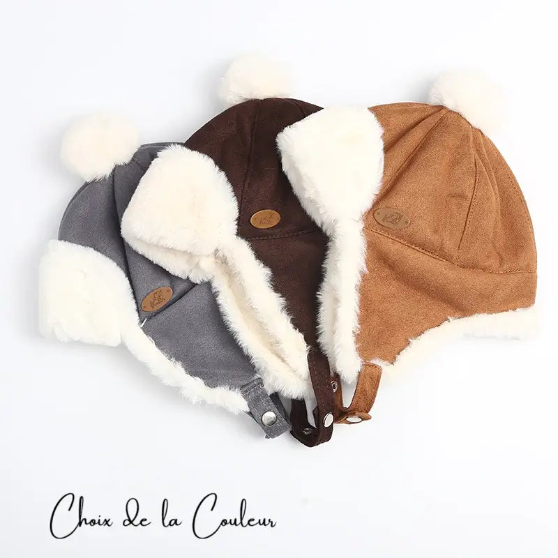 Three Kids' Chapkas in brown, khaki and grey suede, laid flat to show off their faux fur lining and warm, enveloping design.