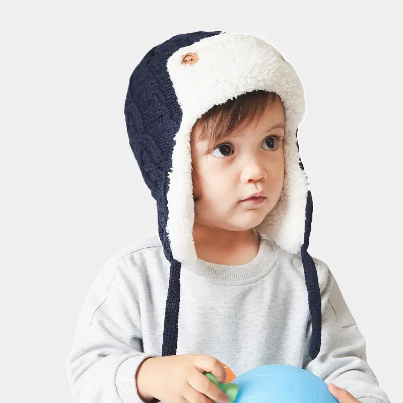 Kinder-Chapka Marineblauer und weißer Strick mit warmem Futter – Ein kleiner Junge trägt eine marineblaue Strickmütze mit Fleece-Innenseite. Ein ideales Accessoire, um der Kälte bequem zu begegnen.