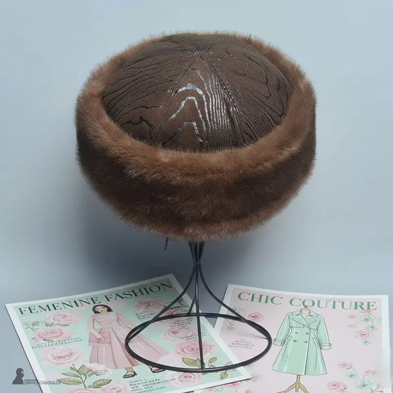Faux fourrure Chapka in brauner Kunstfell mit braunem Innenfutter, runde Chapka-Form, von oben auf einem Ständer, in neutraler Innenumgebung - Cagoules Raum.