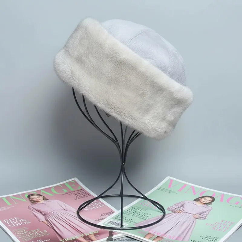 Faux-Fur-Chapka aus hellgrauem Kunstfell mit passendem Textiloberteil, weiche und schützende Chapka-Form, Seitenansicht auf einem Ständer, in einem Innenraum vor neutralem Hintergrund präsentiert - Espace Cagoules.