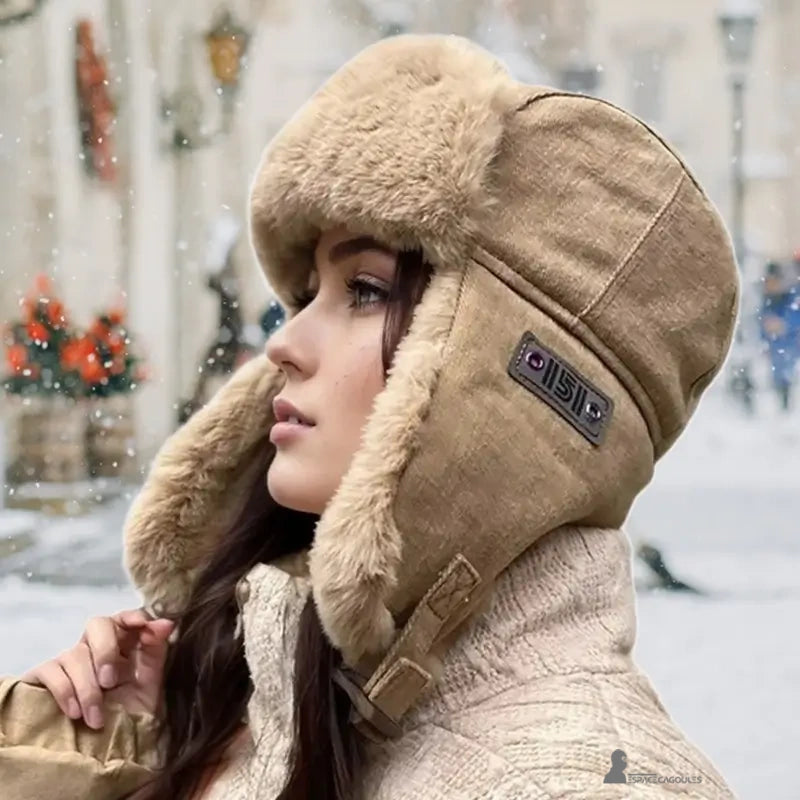 Beige winter women's hat worn by a woman in the city under the snow with light decoration