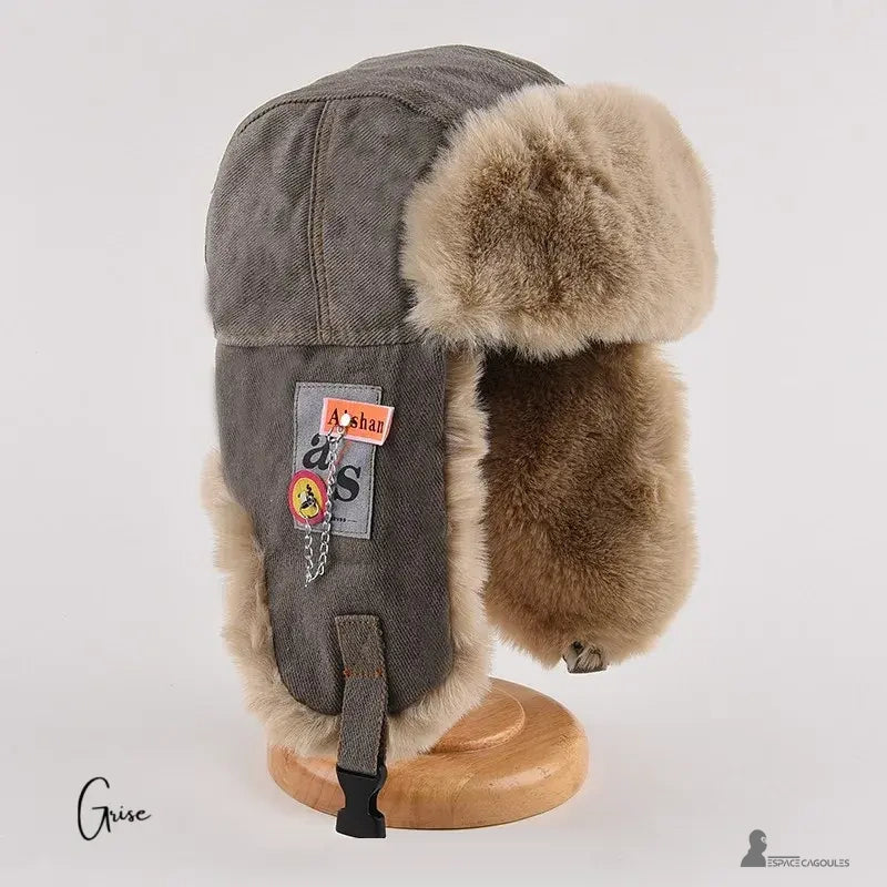 Women's winter chapka grey pattern with beige fur exposed on wooden base