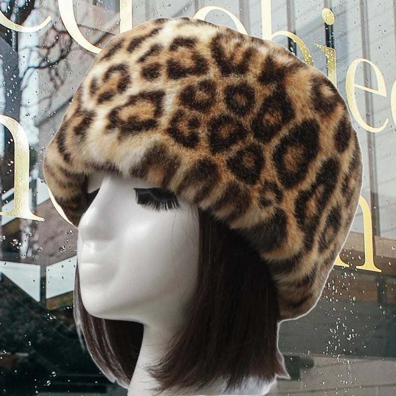 Leopard hat in faux fur with feline motifs, worn outdoors on a mannequin. Warm and stylish winter accessory for cold days.