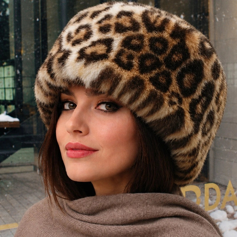 Leopardenmütze aus Kunstfell mit tierischen Mustern, im Freien auf einem Model getragen. Elegantes und warmes Winteraccessoire für kalte Tage.