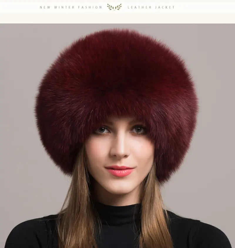 Elegante Frau, die eine russische Chapka aus echtem burgunderrotem Pelz trägt, mit einem luxuriösen und voluminösen Design. Ein raffiniertes Winteraccessoire, ideal, um der Kälte mit Eleganz und Vornehmheit zu begegnen.