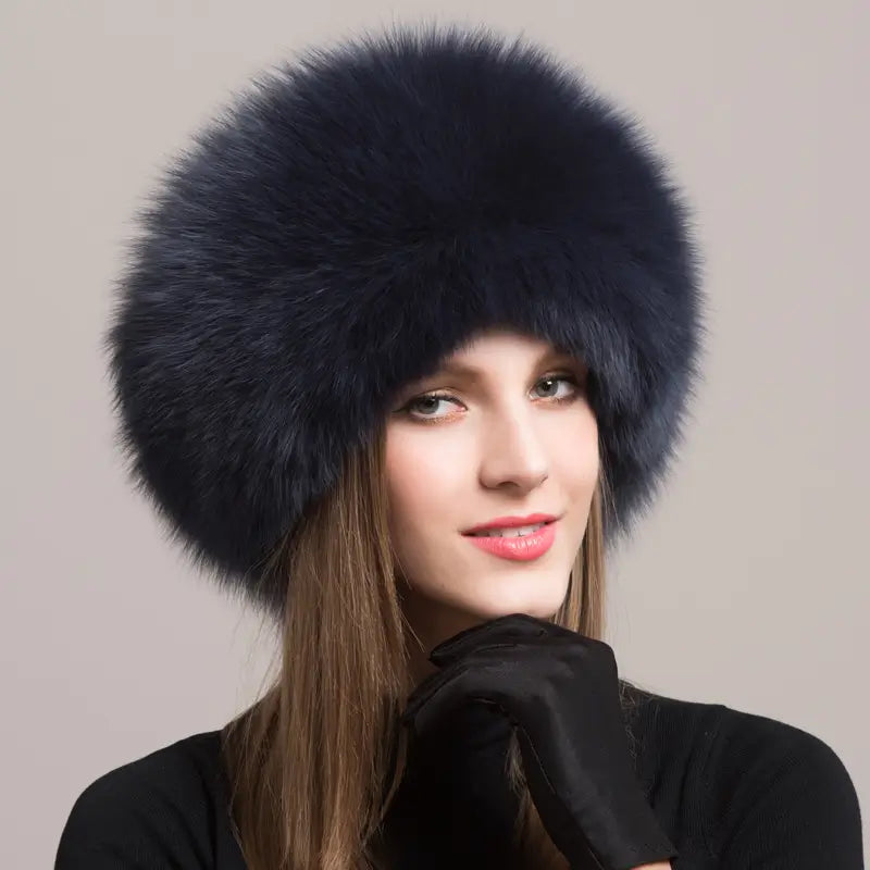 Elegante Frau trägt eine russische Chapka aus echtem dunkelblauem Fell mit einem voluminösen und raffinierten Finish. Ein luxuriöses Winteraccessoire, ideal, um der Kälte stilvoll zu trotzen.