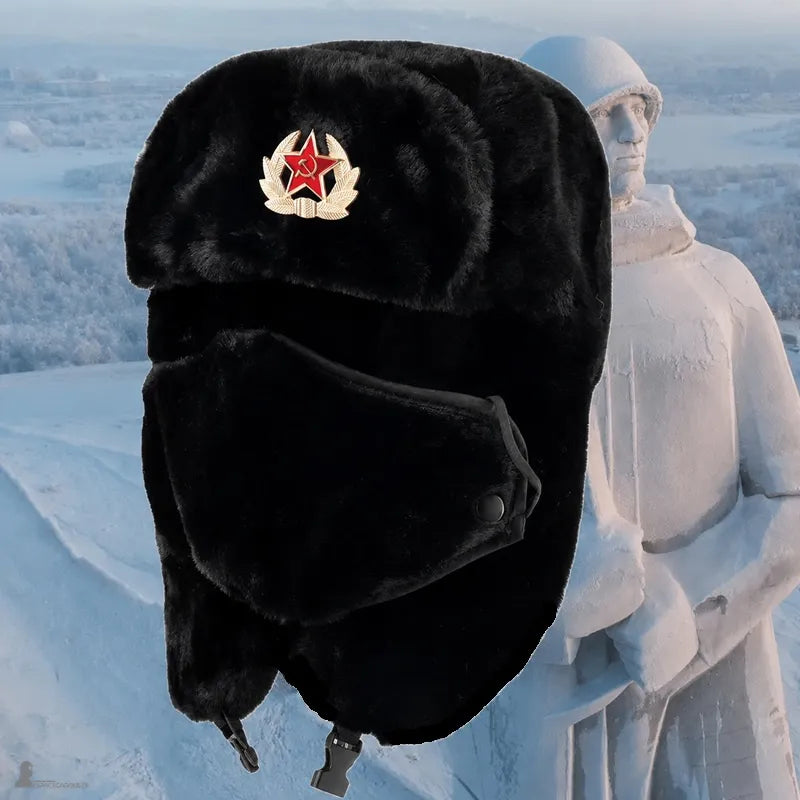 Chapka soviétique noire en fourrure avec insigne étoile rouge et masque, suspendue devant une statue de soldat enneigée - Espace Cagoules