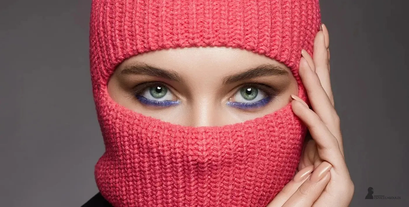 Cagoule femme tricotée rose vif couvrant la bouche et le nez, gros plan sur les yeux verts maquillés, fond neutre – Cagoule Femme - Espace Cagoules