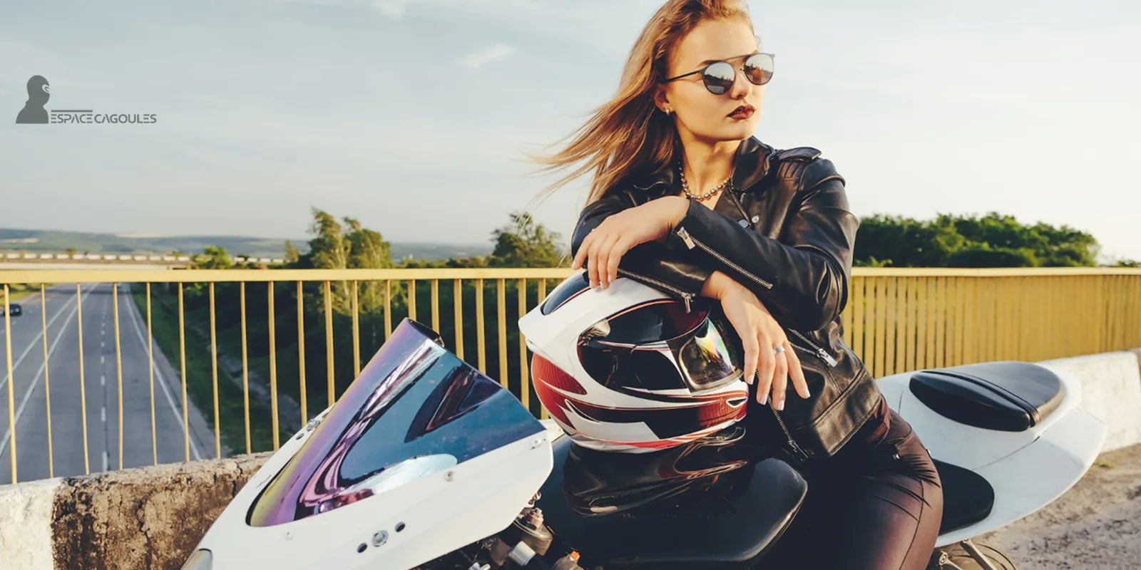 Cagoule Moto Été – Motarde en blouson cuir posant sur sa moto avec casque, symbolisant élégance, fraîcheur et sécurité estivale