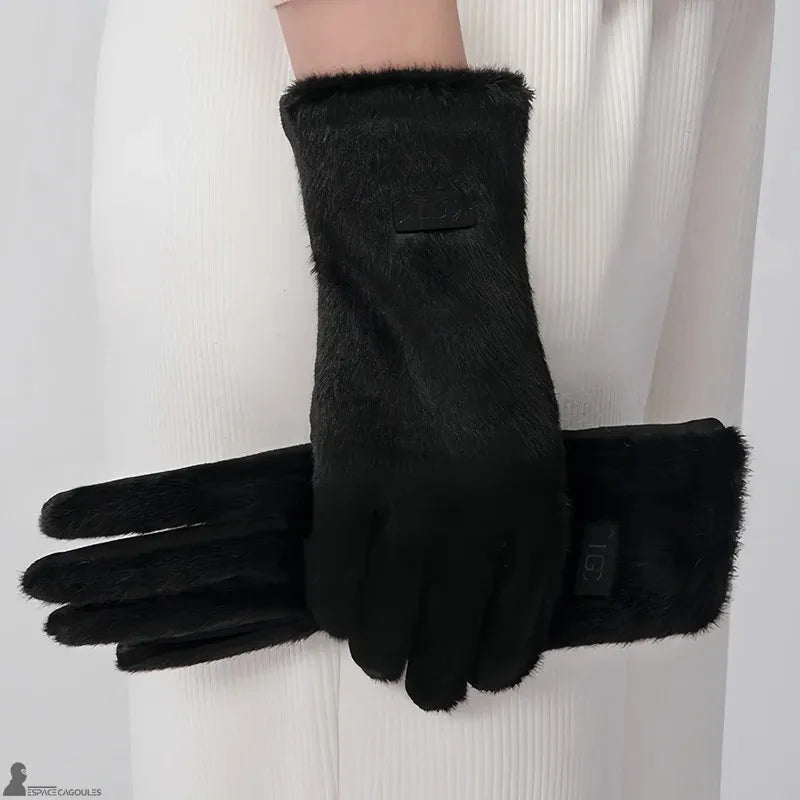 Warme Handschuhe für Frauen in Schwarz, mit einem Obermaterial in Felloptik, eng anliegendem Schnitt und fünf Fingern, getragen in einem hellen Innenraum - Cagoules Raum.