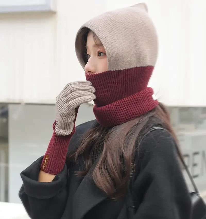 Woman wearing a beige and burgundy wool balaclava, matched with beige wool women's gloves. Stylish and warm winter accessory, ideal for cold days.