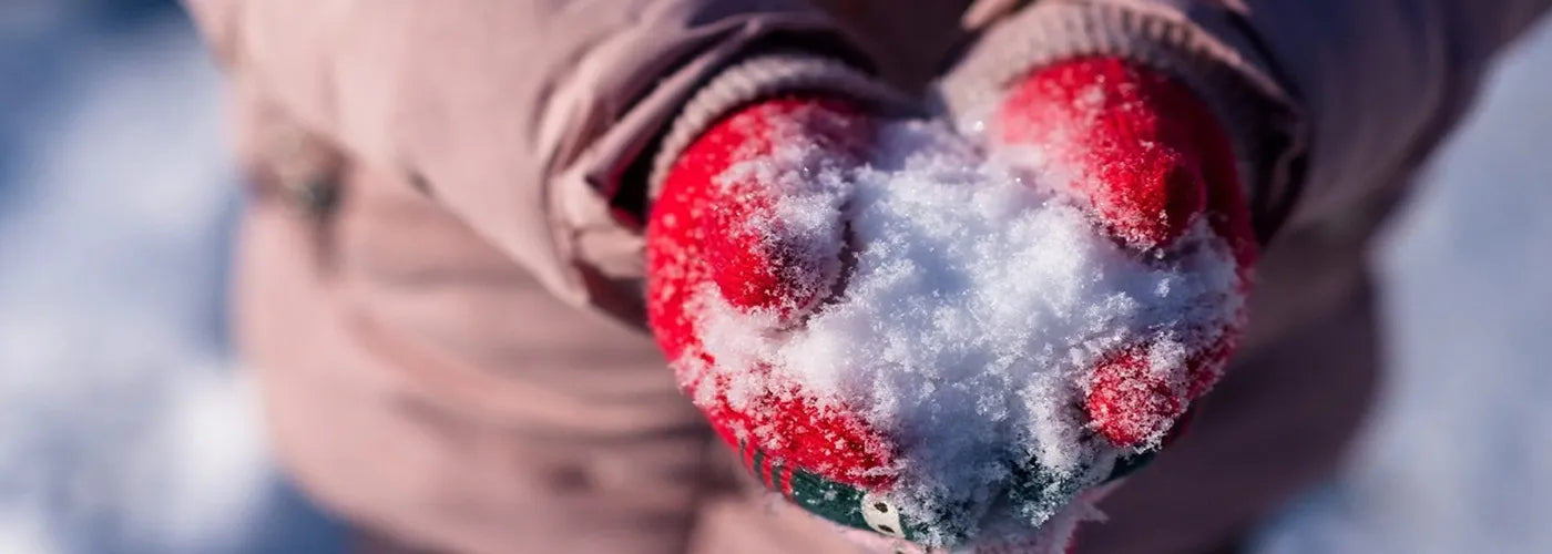 Mains d’un enfant en gants rouges tenant une boule de neige fraîche en extérieur, atmosphère hivernale et tenue chaude – Espace Cagoules