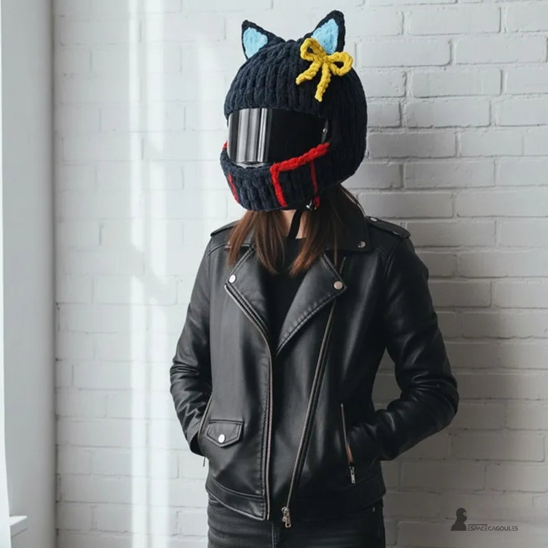 Femme en blouson de cuir portant une housse cagoule pour casque Moto noire avec nĆud jaune et bordure rouge, posant contre un mur blanc, Espace Cagoules