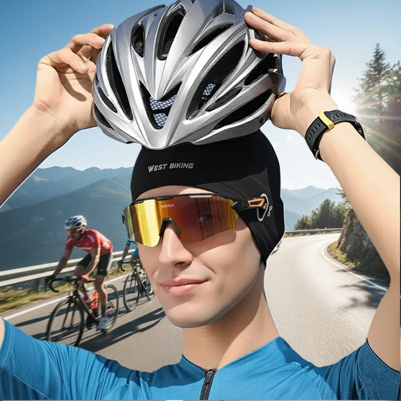 Sous Casque vélo été noir West Biking porté par cycliste avec casque argenté et lunettes, sur route de montagne ensoleillée