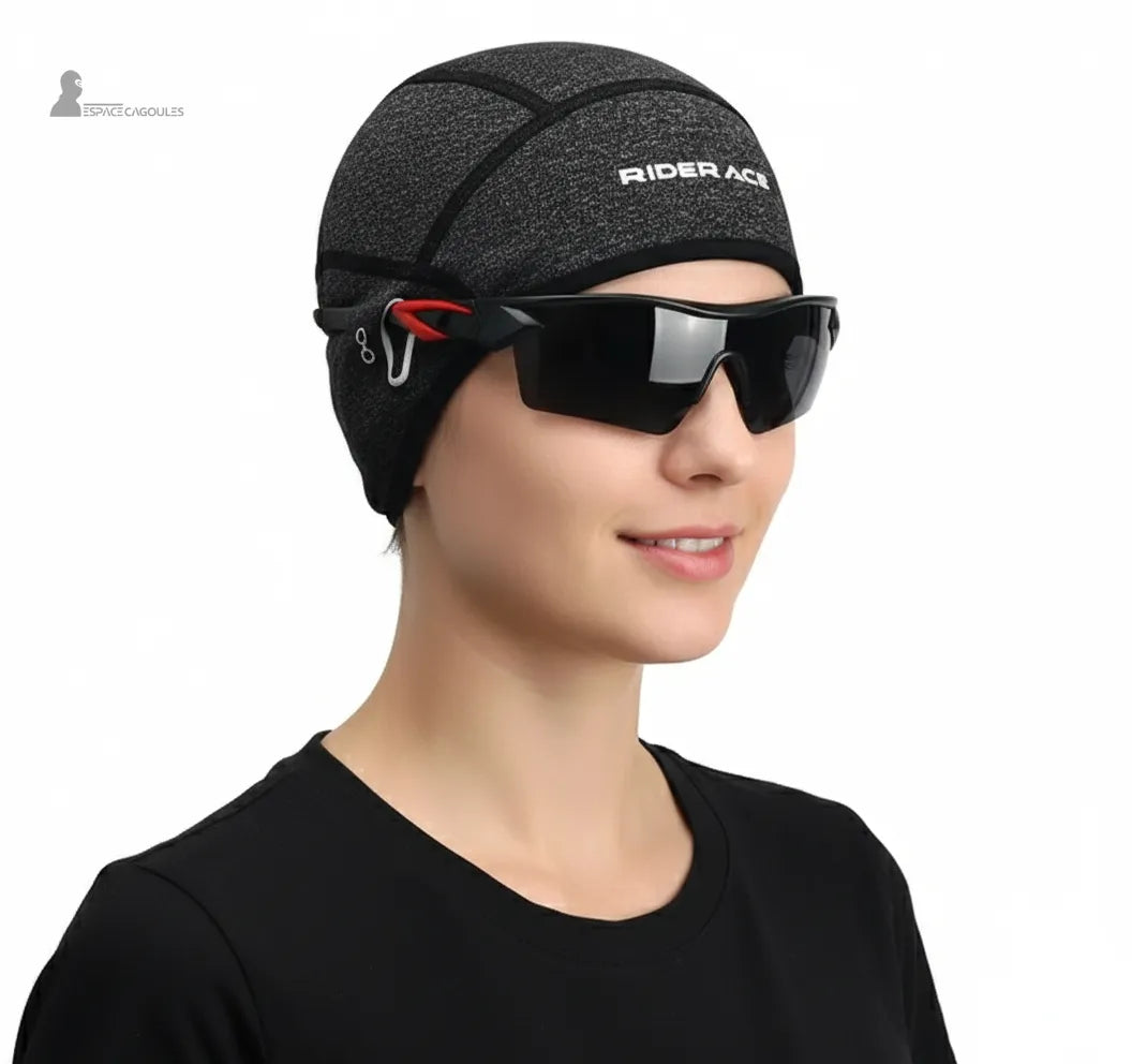 Sous casque vélo route gris porté par femme avec lunettes de sport noires, adapté au cyclisme route et aux entraînements par temps froid