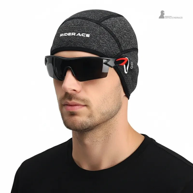 Sous casque vélo route gris porté par homme avec lunettes de sport noires, idéal pour protéger la tête et les oreilles lors des trajets cyclistes en hiver