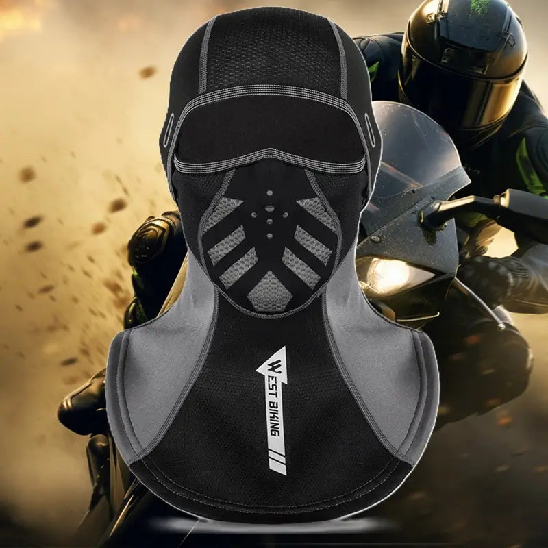 Cagoule pour moto en noir et gris, dotée d'un design ergonomique avec zones respirantes et protège-cou allongé, idéale pour les motards affrontant des conditions difficiles, en arrière-plan un motard sur une moto sportive.