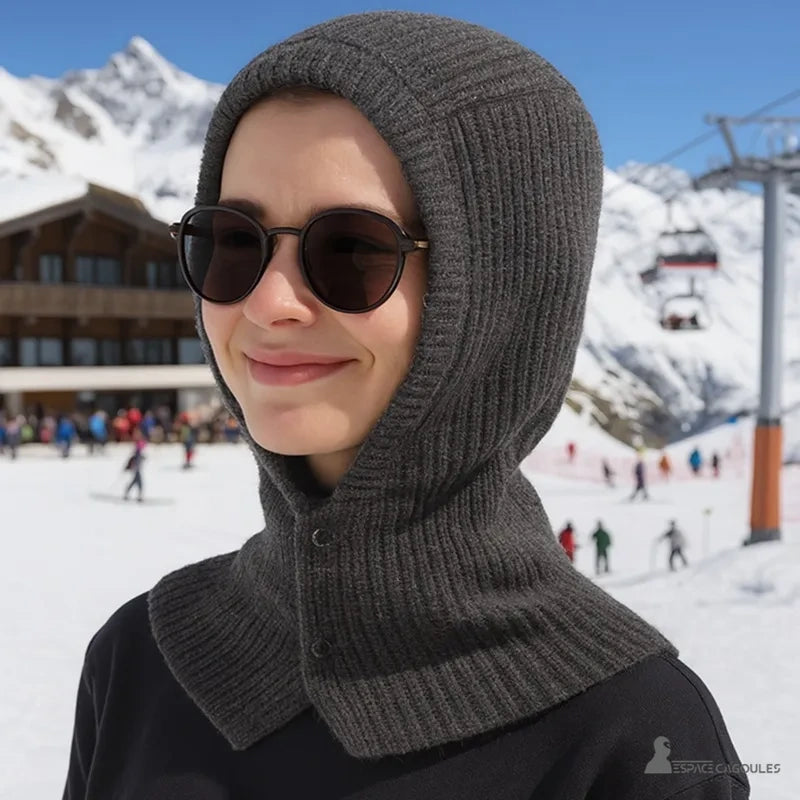Balaclava Cagoule Tricot portée par une femme souriante avec lunettes noires dans une station de ski enneigée