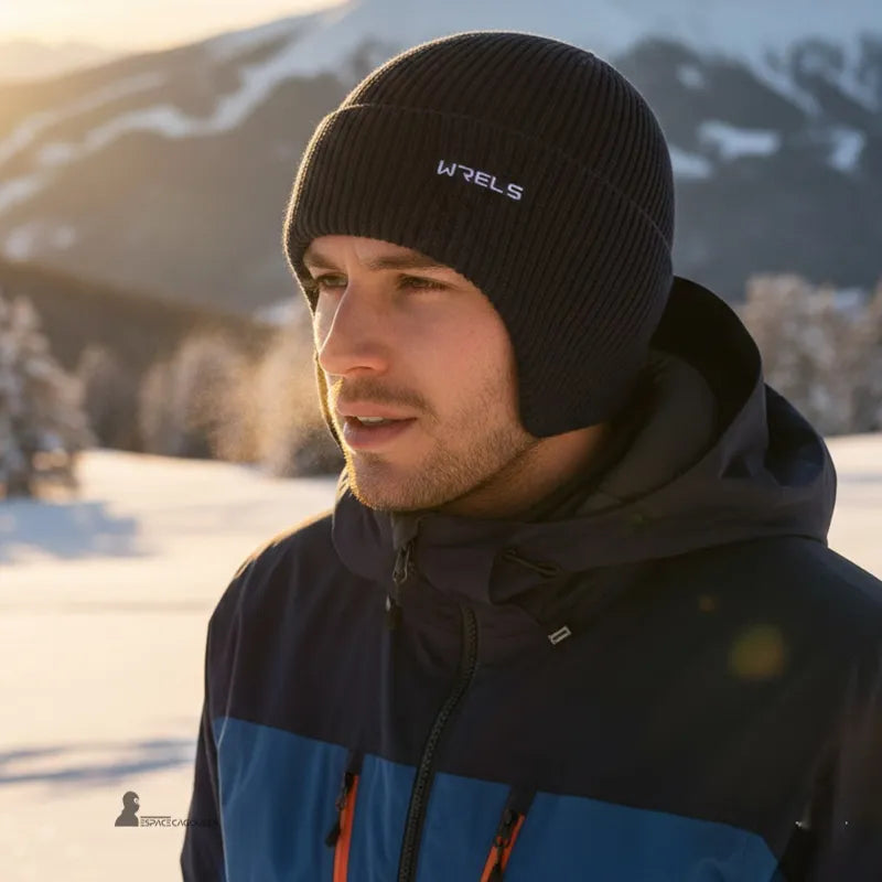 Bonnet sous casque ski noir en fibre synthétique tricotée porté par un homme, forme ajustée protégeant les oreilles, vue portée en extérieur montagne par temps froid - Espace Cagoules