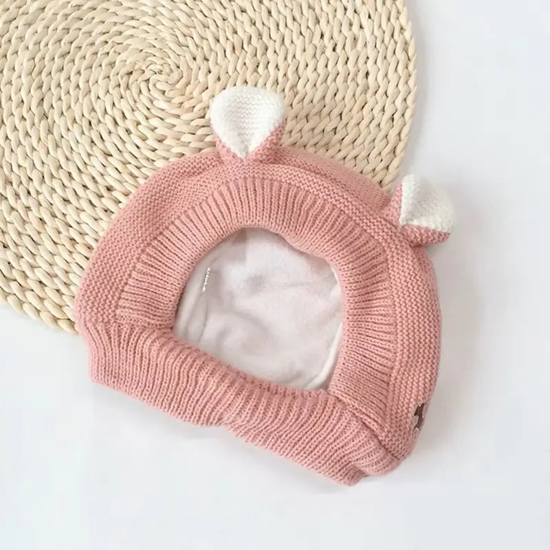 Cagoule bébé 6 à 36 mois rose en tricot doux, avec des petites oreilles blanches et doublure chaude en polaire. Idéale pour protéger la tête et le cou du froid.