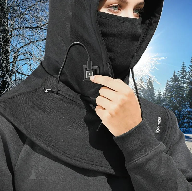 Cagoule chauffante : Gros plan d'une personne portant une cagoule noire, un masque facial et des lunettes de soleil, en train d'appuyer sur un bouton de commande USB. L'arrière-plan est une forêt enneigée.