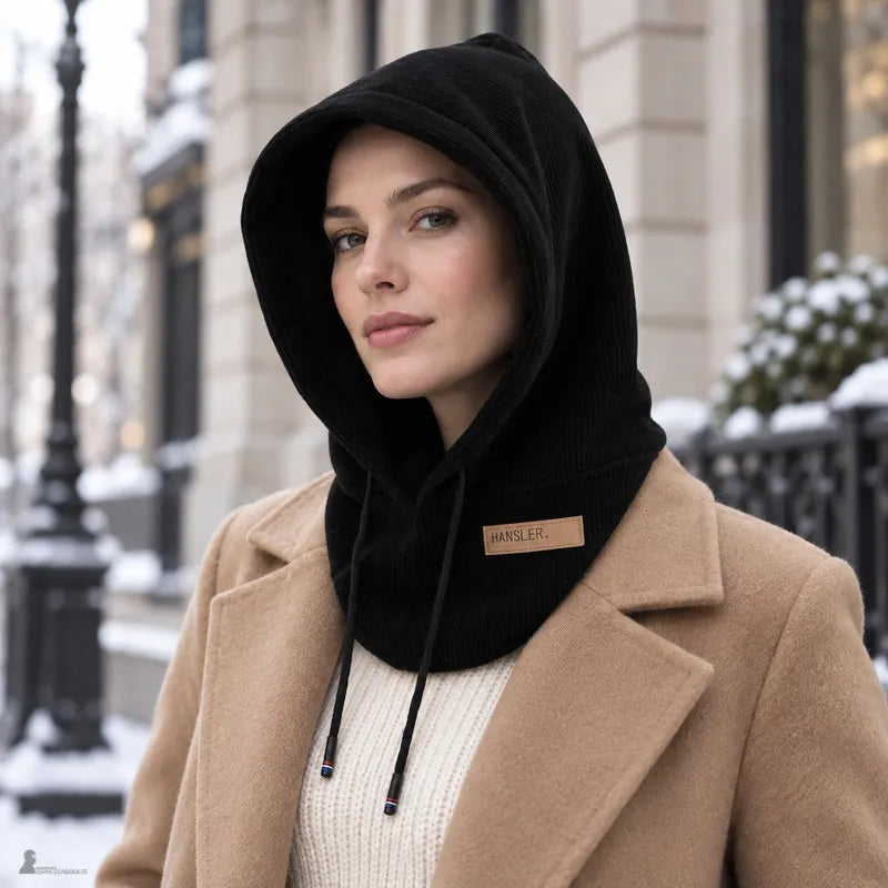 Femme en manteau camel dans une rue enneigée, capuche en velours côtelé noir remontée sur la nuque, cordon de serrage apparent - Espace Cagoules