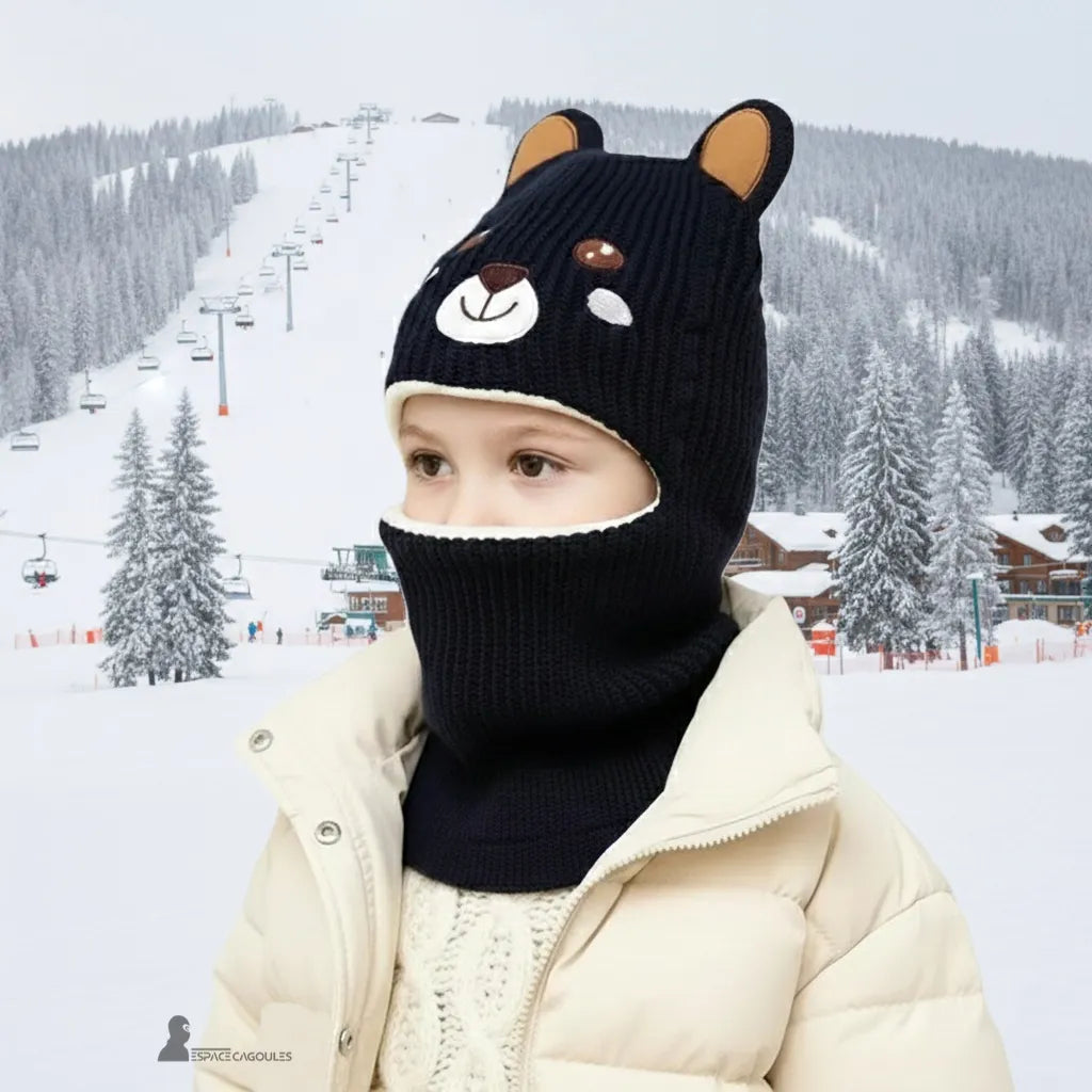 Passamontagna per bambini di 5 anni che indossano un passamontagna orso blu navy su una pista innevata con impianti di risalita sullo sfondo che garantiscono la massima protezione nel freddo estremo – Espace Cagoules