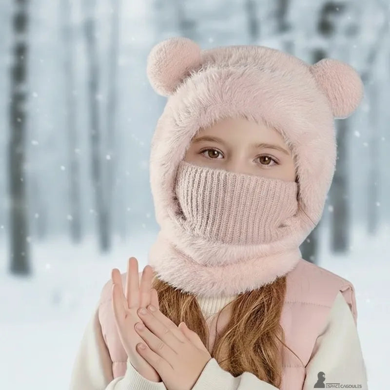 cagoule enfant fille – Enfant portant une cagoule rose relevée avec masque tricoté couvrant le bas du visage, en extérieur dans une forêt enneigée avec chute de neige – Espace Cagoules