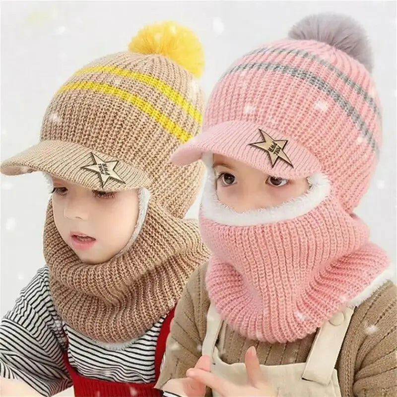 Deux enfants portant une cagoule enfant en laine tricotée avec visière et pompon : l'une beige à rayures jaunes, l'autre rose à rayures grises. Ces cagoules couvrent la tête, le cou et la bouche, idéales pour protéger les enfants du froid pendant l'hiver.