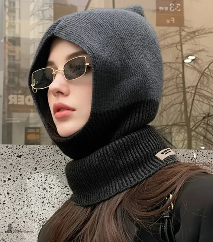 Cagoule femme en laine noire et grise vue de profil, portée en extérieur urbain avec design moderne et col épais protecteur