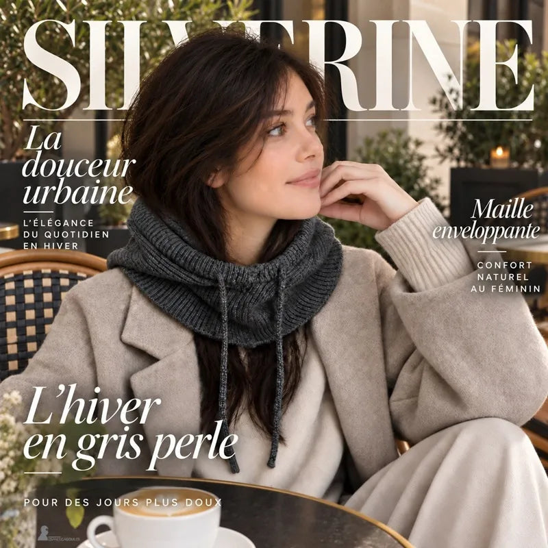 Femme assise en terrasse avec la cagoule Silverine gris foncé portée capuche rabattue sur la nuque, cordons sur un manteau beige - Espace Cagoules